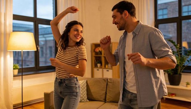 Young couple dancing in cozy urban apartment, smiling and enjoying relaxed evening together