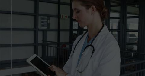 Female Doctor Using Digital Tablet in Hospital Corridor