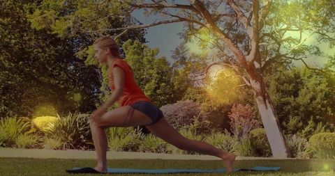 Outdoor fitness lunge woman performing forward lunge on blue mat with sunlight flare