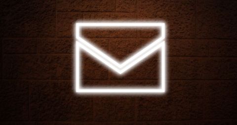 Neon envelope icon glowing on brick wall background