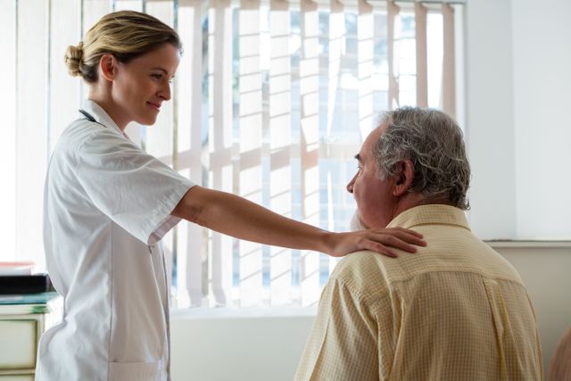 Female doctor placing hand on senior man's shoulder, showing compassion and support in nursing home. Ideal for healthcare, elderly care, medical consultation, and patient support themes.