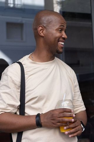 Smiling african man holding fresh juice outside storefront urban street lifestyle portrait