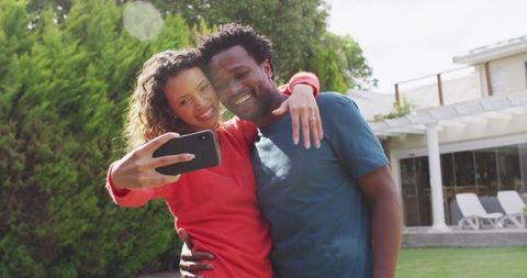 Happy Biracial Couple Taking Selfie After Proposal in Sunlit Garden
