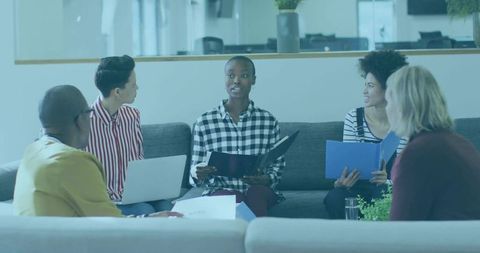 Diverse Team Discussion in Office Lounge with Laptops