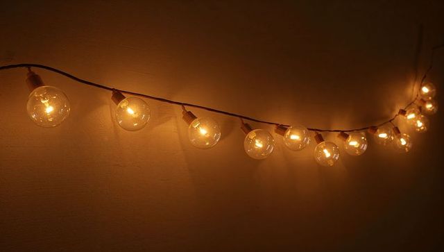 Glowing Globe String Lights Casting Warm Amber Halos on Textured Wall, Cozy Ambient Decor