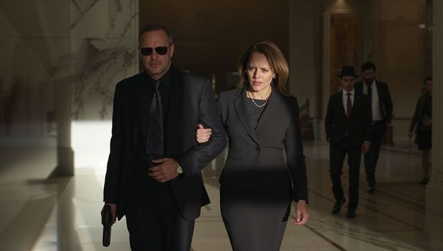 Walking confident female executive being escorted by bodyguard through marble corridor
