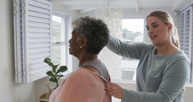 Younger Caregiver Assisting Senior Woman with Dressing in Bright Room - Download Free Stock Images Pikwizard.com