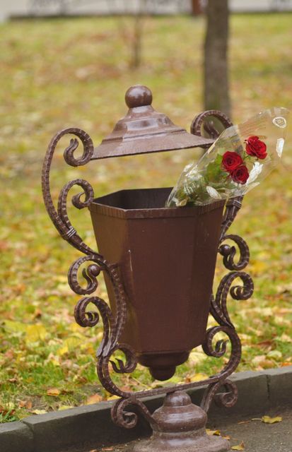 Rustic metal bin in park with discarded bouquet of red roses symbolizes lost love, breakups, or abandoned romance. Perfect for use in articles, blogs, or stories about heartbreak, environmental issues, or urban decor.