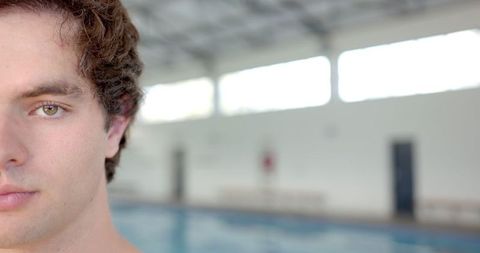 Young Man Swimming at Indoor Pool with Focused Expression