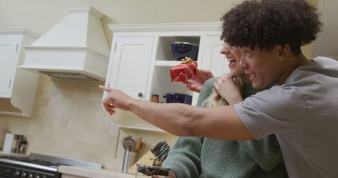 Happy Couple Embracing with Gift in Modern Kitchen