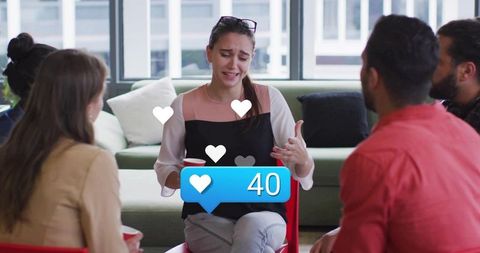 Young professional woman sharing emotional story during casual office break group discussion