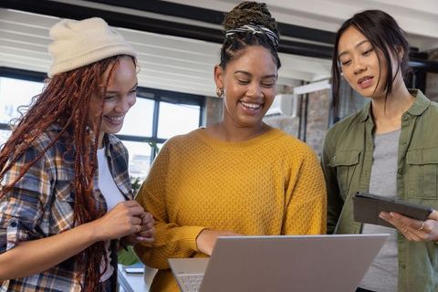 Diverse Female Coworkers Reviewing Content on Laptop at Office