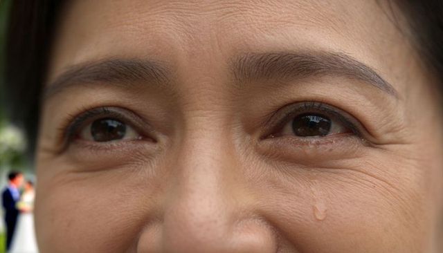 Teary close-up portrait of middle-aged asian woman showing emotion at outdoor celebration