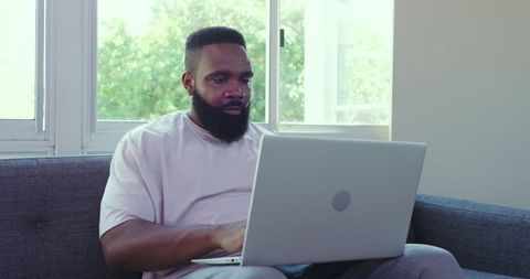 African American Man Focused on Laptop in Cozy Home