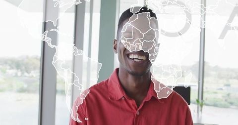 Smiling professional wearing red shirt with world map overlay in modern office hub