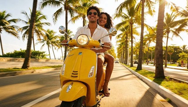 Young couple riding yellow scooter on palm-lined seaside boulevard at golden hour