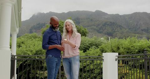 Happy Couple Relaxing Outdoors Against Scenic Mountains