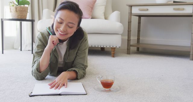 Young Woman Writing in Notebook While Relaxing on Carpet - Download Free Stock Images Pikwizard.com