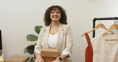 Smiling small business owner packing ecommerce orders in boutique clothing studio