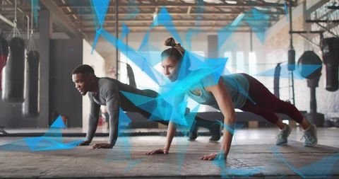 Couple performing plank workout in industrial gym with blue digital overlay