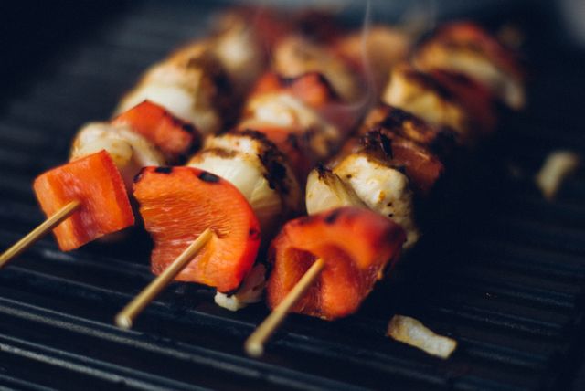 Delicious shish kebabs with red peppers and chicken grilling over charcoal. Ideal for illustrating summer outdoor cooking, barbecue parties, healthy eating, and food preparation. Suitable for food blogs, recipe websites, and culinary magazines.