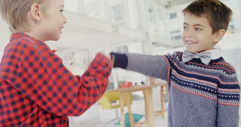 Two Boys Sharing Playful Fist Bump Indoors