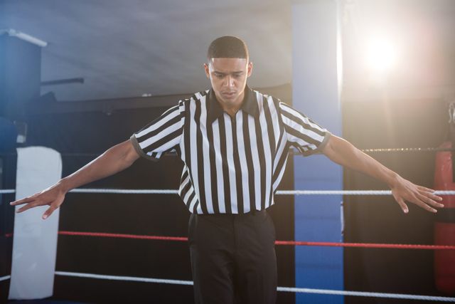 Male referee gesturing with arms outstretched in boxing ring