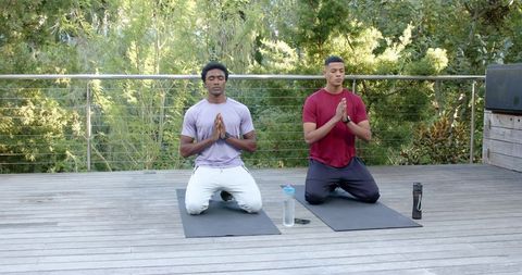 Diverse friends meditating on yoga mats outdoors for mindfulness and well-being
