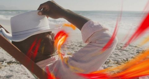 Relaxing on beach lounger adjusting white hat with vibrant red light streaks, coastal vacation mood