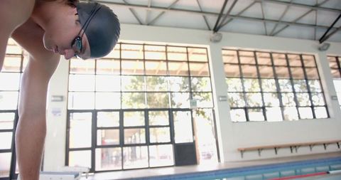 Male swimmer preparing to dive in indoor pool for competition