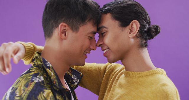 Couple sharing a tender, romantic moment by touching foreheads and smiling. This can be used to illustrate love, affection, and intimate relationships in advertisements, social media campaigns, and articles about love and relationships, especially in the LGBTQ+ community.
