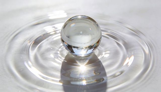 Crystal sphere creating circular water ripples with bright reflections and refraction