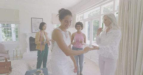 Bride trying on lace wedding gown with tailor and friends sharing champagne at home