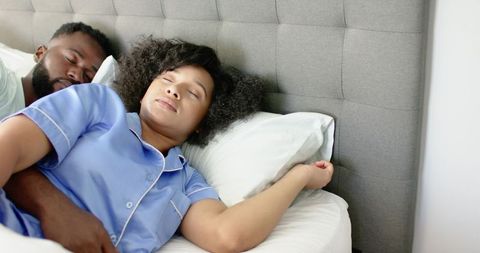 Hispanic and African American Couple Sleeping Cuddling in Bed with Tufted Headboard