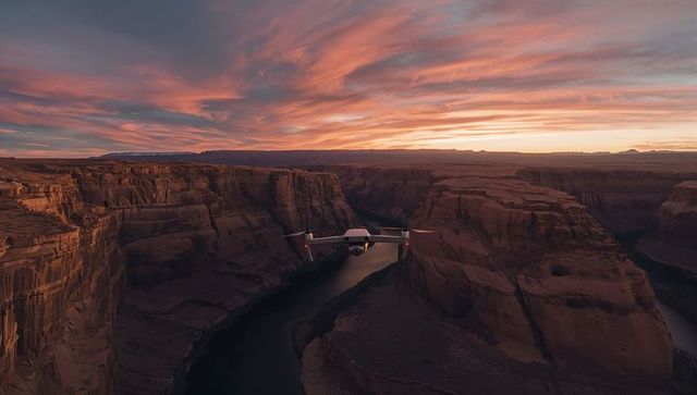 Hovering drone capturing sunset over sandstone canyon with winding river and dramatic sky