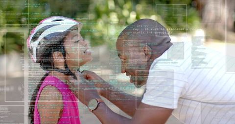 Caregiver fastening bicycle helmet for child on sunny park path with digital code overlay