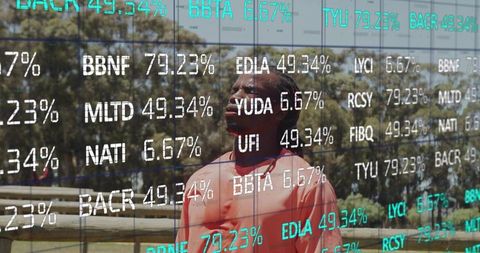Man standing in park wearing coral shirt looking up with digital stock ticker overlay