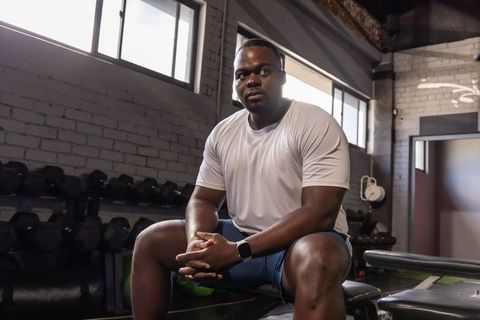Focused african athlete resting on bench in industrial gym during strength training
