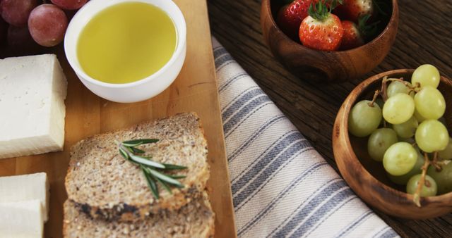 Healthy breakfast spread on table with variety of options. Ingredients include whole grain bread, grapes, strawberries, cheese and bowl of olive oil. Ideal for promoting healthy eating, culinary blogs, recipe websites, and food-related advertisements.