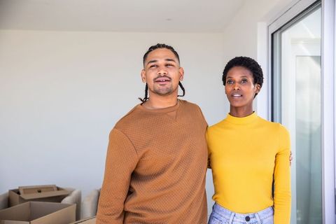 Happy Couple Relaxing in New Home by Large Windows