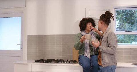 Couple enjoying coffee on countertop in modern bright kitchen, cozy intimate moment