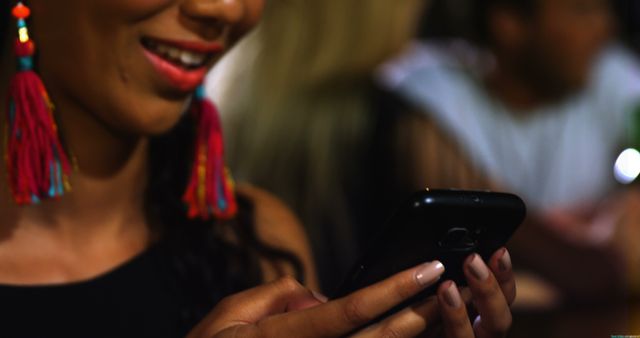 Woman Smiling Looking at Smartphone in Colorful Earrings - Download Free Stock Images Pikwizard.com