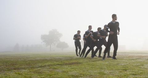 Male Athletes in Synced Run through Foggy Field