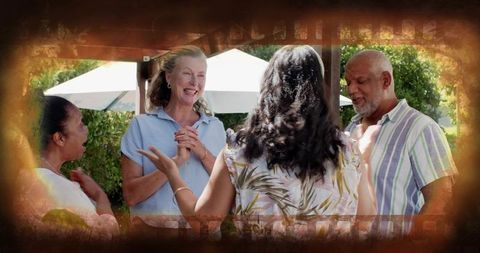 Friends and family chatting and laughing under pergola in sunlit garden gathering