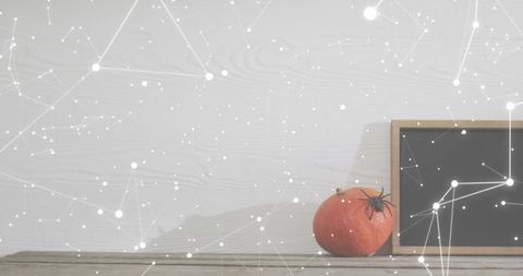 Minimalist autumn still life featuring pumpkin and chalkboard with constellation overlay