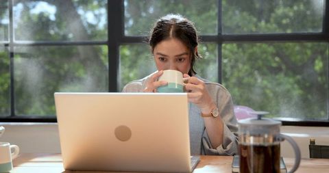 Businesswoman Working on Laptop, Enjoying Morning Coffee at Office