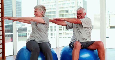 Senior Couple Exercising on Stability Balls with Smiles