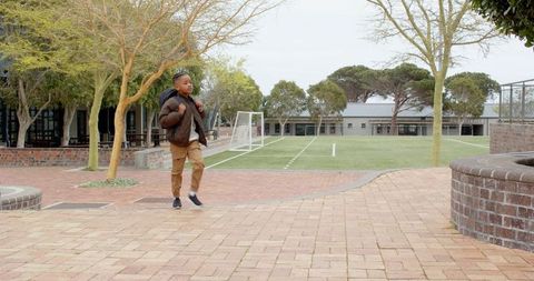 Young boy walking through school yard with backpack
