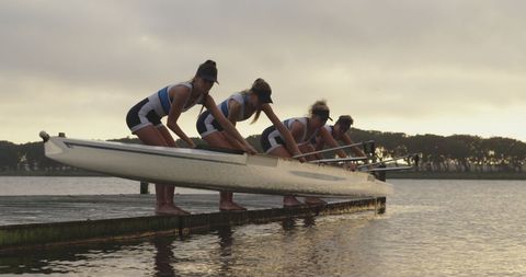 Women Preparing Rowing Boat at Dawn for Team Practice
