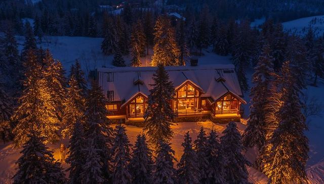 Glowing alpine timber lodge night view with snow-covered pines and warm interior lights